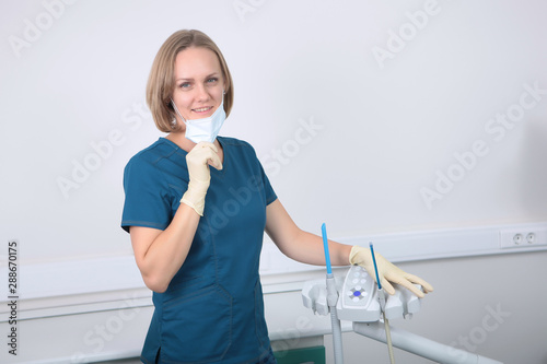 Woman dentist doctor removes a medical mask. Koncept of prevention and treatment of teeth.