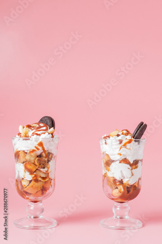 Sweet dessert in glass with biscuit and whipped cream on pink bsckground  selective focus and blank space