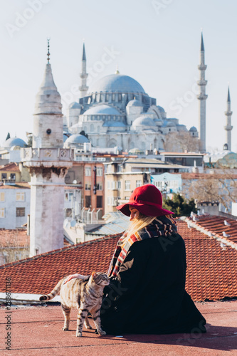Canvas Print Blond woman stroking a cat on the roof with a view to the mosque, Istanbul, Turkey