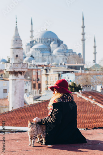 Canvas Print Blond woman stroking a cat on the roof with a view to the mosque, Istanbul, Turkey
