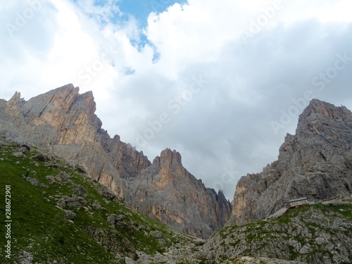 The peaks of the Dolomites of the Sassolungo Massif immersed in the clouds and in the nature of Trentino - Alto - Adige, Near the town of Canazei, Italy - August 2019.