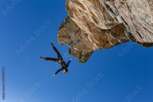 Climber fall from a cliff on a safety rope. extreme climbing. extreme sport, winter season. Mountains and blue sky on the background. Copy space