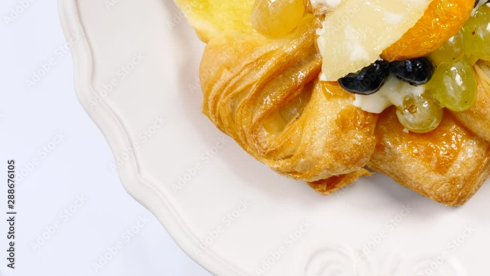 Puff pastry sweet cake decorated with fresh variety fruits slices rotating on white plate. Top view Puff pastry sweet cake decorated with fresh variety fruits slices rotating on white plate. Top view