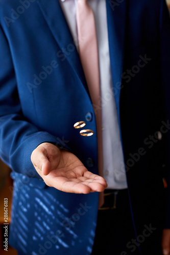 Groom holding wedding rings on the palm, wedding ring in groom hand. A man throws the rings up..