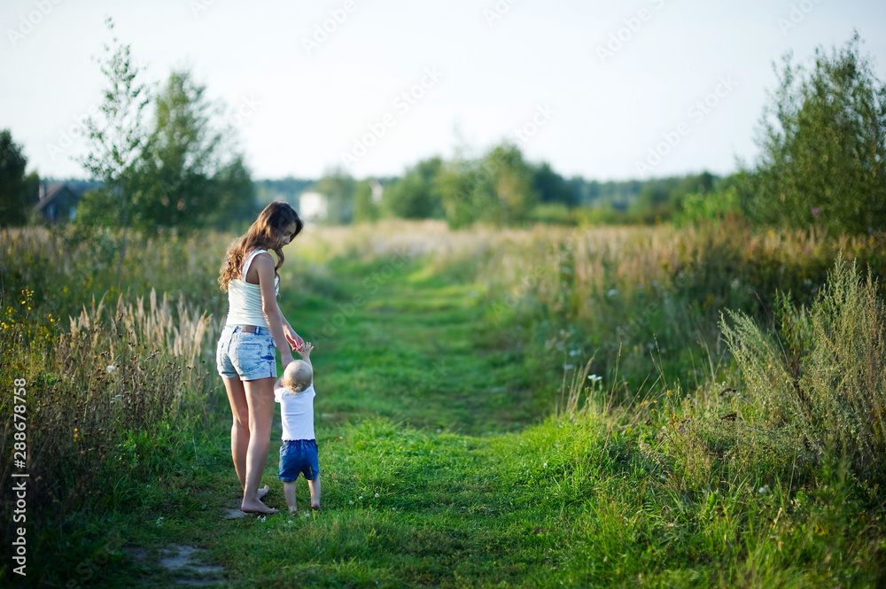 young mother walks with her little daughter barefoot on a country road at sunset. The nanny walks with the child. copy space young mother walks with her little daughter barefoot on a country road at sunset. The nanny walks with the child. copy space