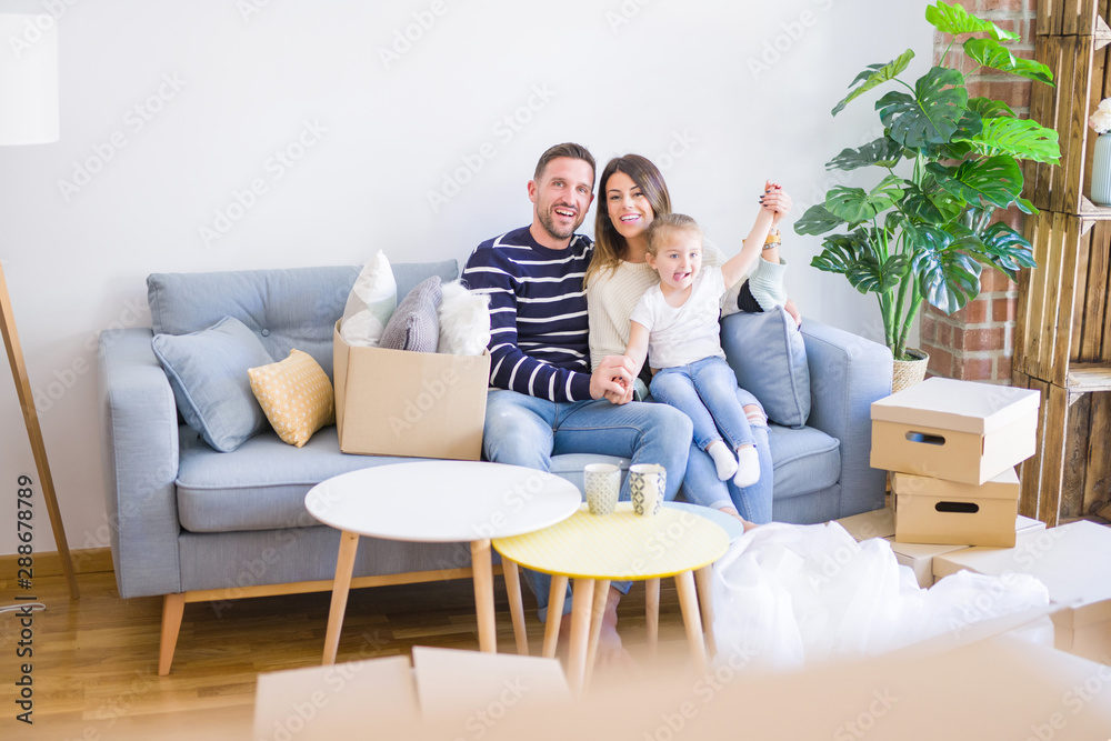 Beautiful family with kid sitting on the sofa drinking coffee at new home around cardboard boxes Beautiful family with kid sitting on the sofa drinking coffee at new home around cardboard boxes