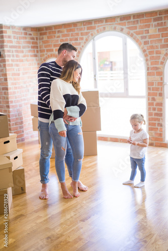 Beautiful family with a kid standing at new home around cardboard boxes © Krakenimages.com