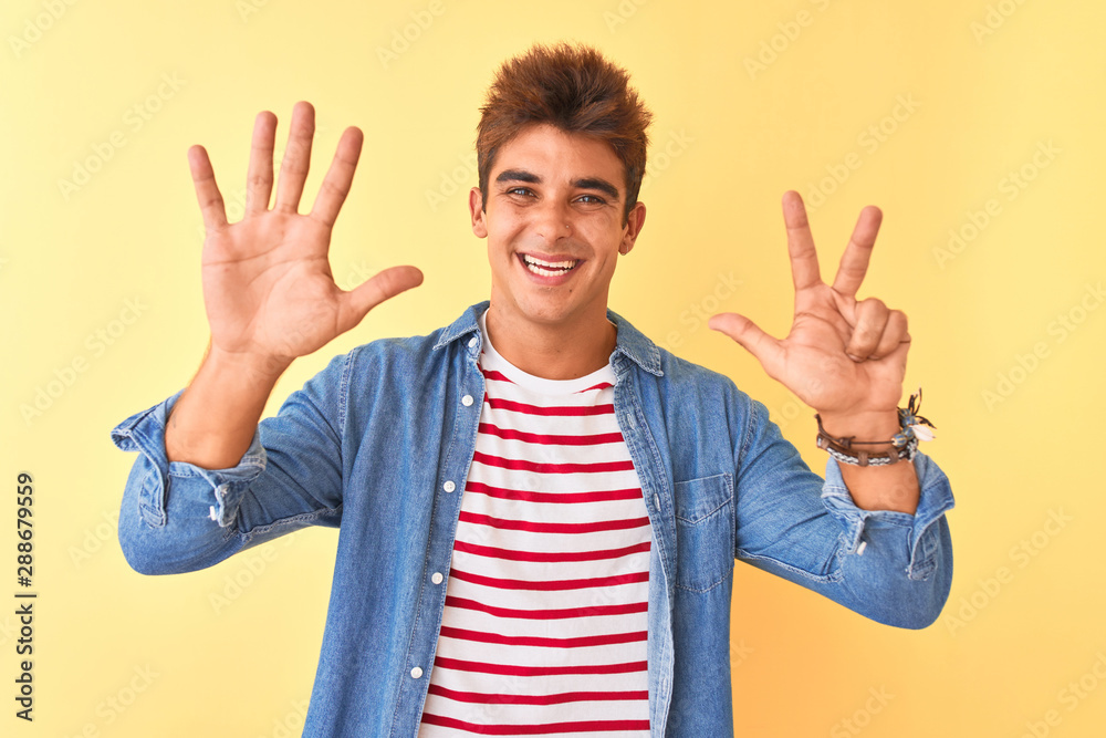 Young handsome man wearing striped t-shirt and denim shirt over isolated yellow background showing and pointing up with fingers number eight while smiling confident and happy. Young handsome man wearing striped t-shirt and denim shirt over isolated yellow background showing and pointing up with fingers number eight while smiling confident and happy.