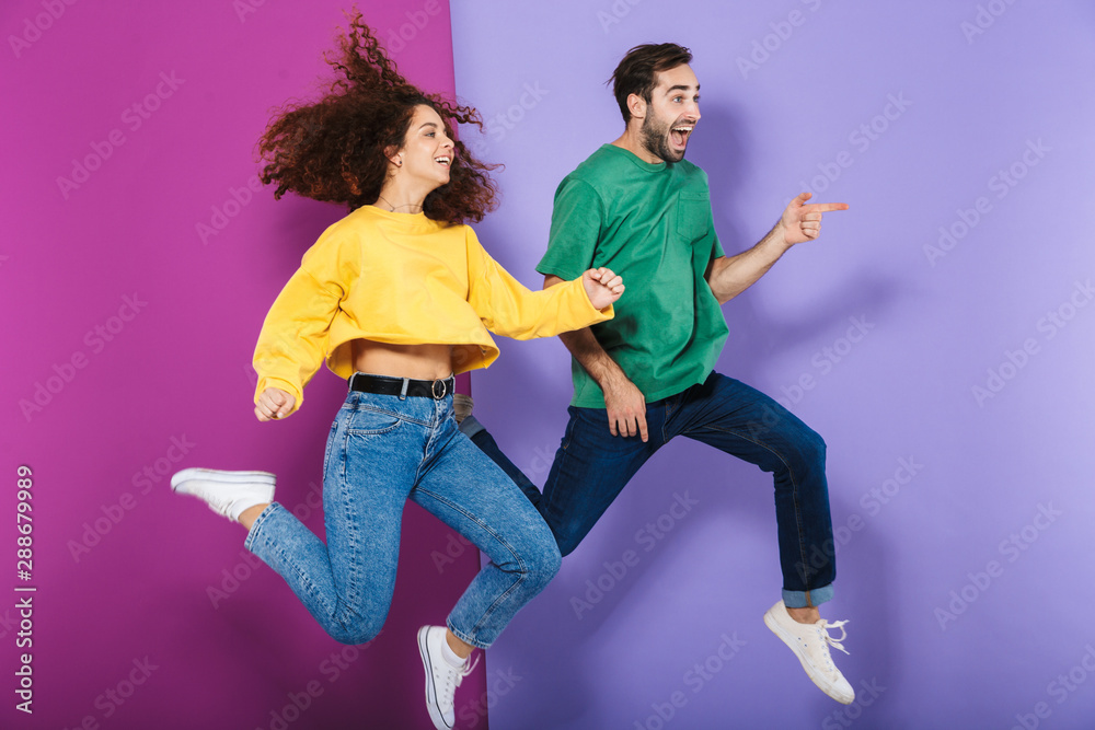 Portrait of happy caucasian couple man and woman in colorful clothing laughing and running together