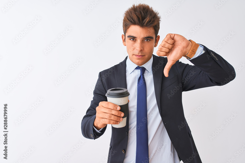 Young handsome businessman wearing suit holding coffee over isolated white background with angry face, negative sign showing dislike with thumbs down, rejection concept Young handsome businessman wearing suit holding coffee over isolated white background with angry face, negative sign showing dislike with thumbs down, rejection concept