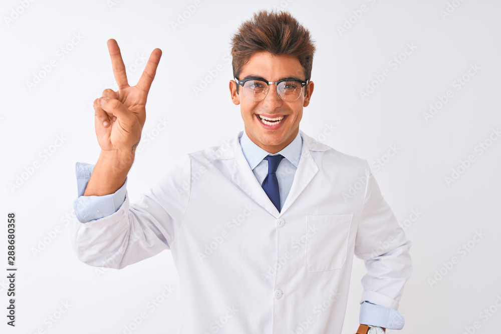 Young handsome sciencist man wearing glasses and coat over isolated white background smiling looking to the camera showing fingers doing victory sign. Number two. Young handsome sciencist man wearing glasses and coat over isolated white background smiling looking to the camera showing fingers doing victory sign. Number two.