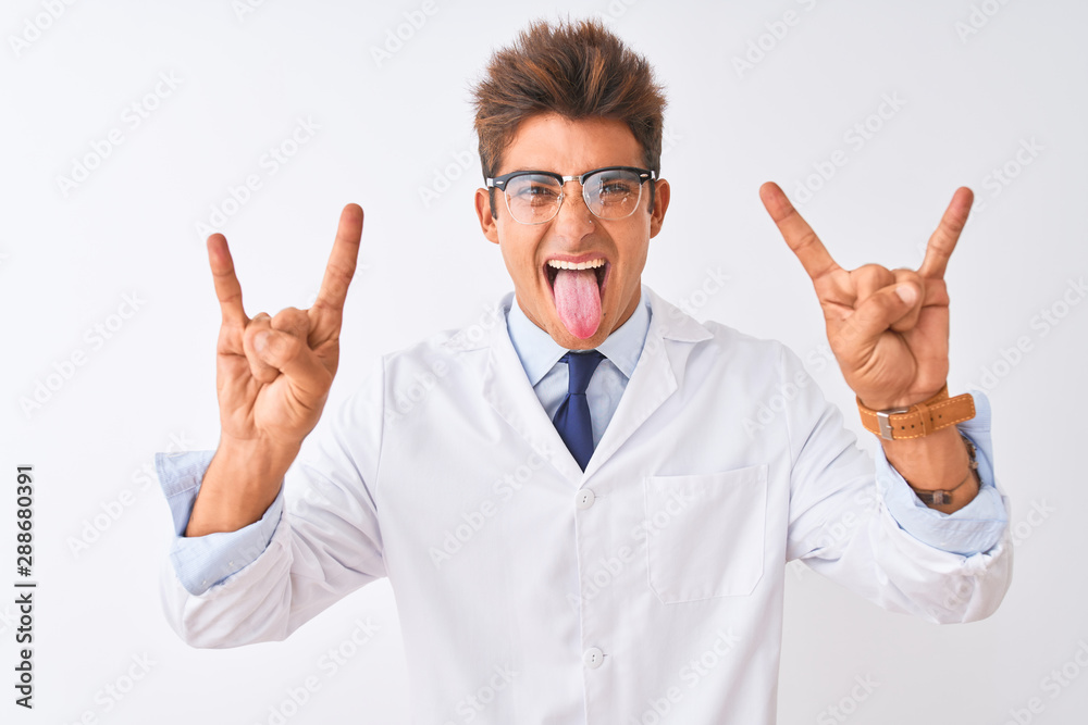 Young handsome sciencist man wearing glasses and coat over isolated white background shouting with crazy expression doing rock symbol with hands up. Music star. Heavy music concept. Young handsome sciencist man wearing glasses and coat over isolated white background shouting with crazy expression doing rock symbol with hands up. Music star. Heavy music concept.