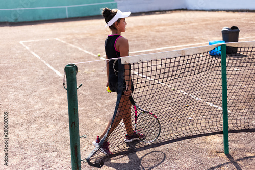 Teenage tennis player girl with racket in hand on court. © Lalandrew