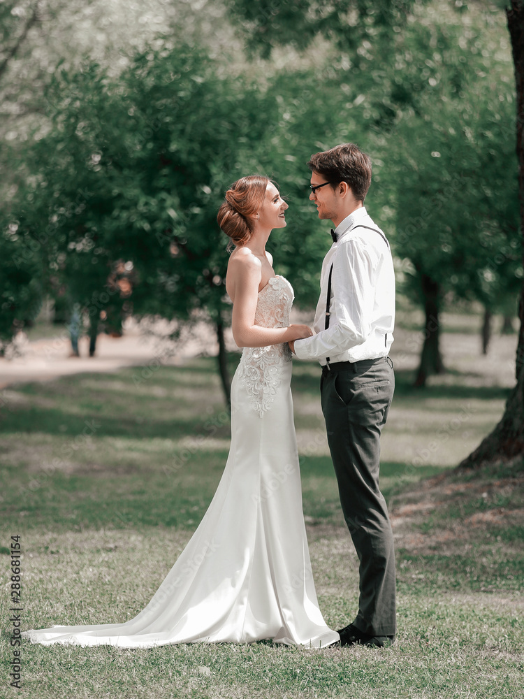 happy newlyweds stand together in a Sunny Park