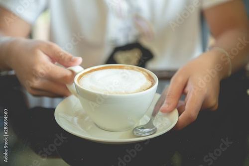 A cup of cappuccino in a woman's hand