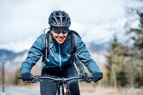 Front view of female mountain biker riding in snow outdoors in winter nature.