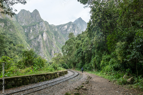 Back view of male hiker with backpack. Tourist man hiking along railroad to Machu Picchu, Peru