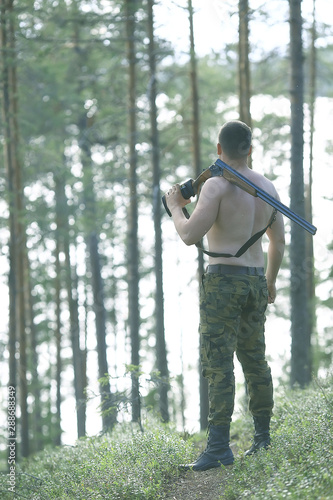 man goes hunting forest summer / landscape in the forest, huntsman with a hunting rifle hunts © kichigin19