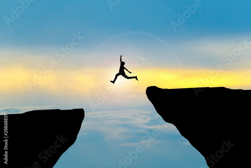 Man jump through the gap between hill.man jumping over cliff photo