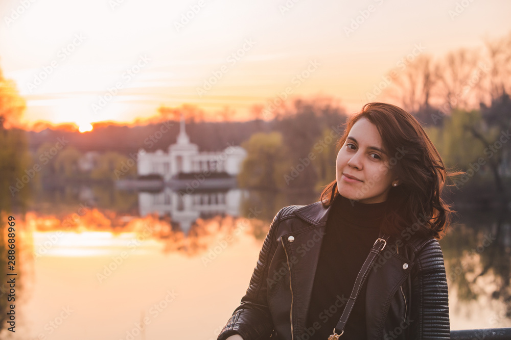 portrait of young pretty woman on sunset river on background