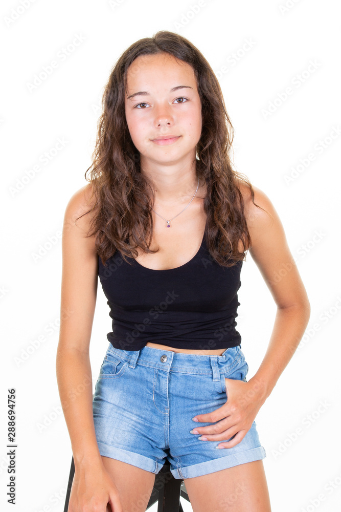 Teenager girl over white wall posing with hand at hip denim short posing beauty slim young woman Teenager girl over white wall posing with hand at hip denim short posing beauty slim young woman