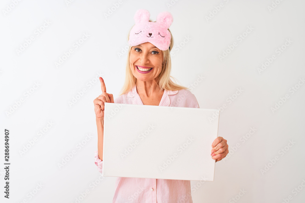 Middle age woman wearing sleep mask pajama holding banner over isolated white background surprised with an idea or question pointing finger with happy face, number one Middle age woman wearing sleep mask pajama holding banner over isolated white background surprised with an idea or question pointing finger with happy face, number one