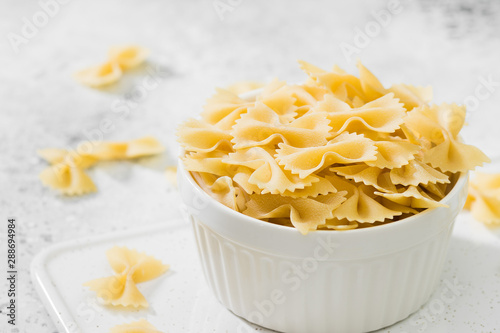 Farfalle pasta in a white bowl on a light background