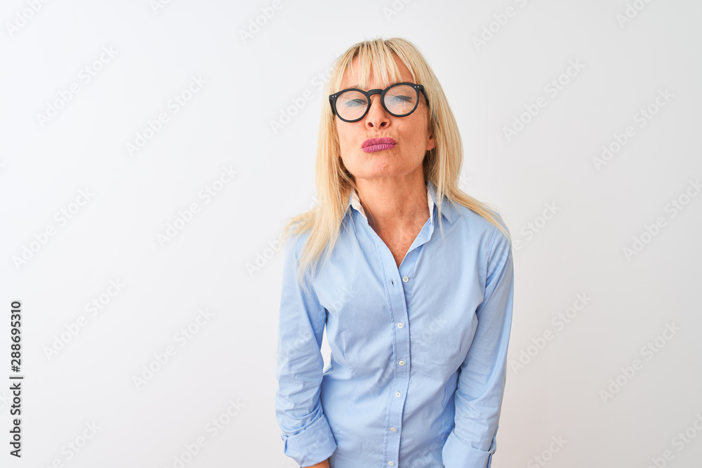 Middle age businesswoman wearing elegant shirt and glasses over isolated white background looking at the camera blowing a kiss on air being lovely and sexy. Love expression.