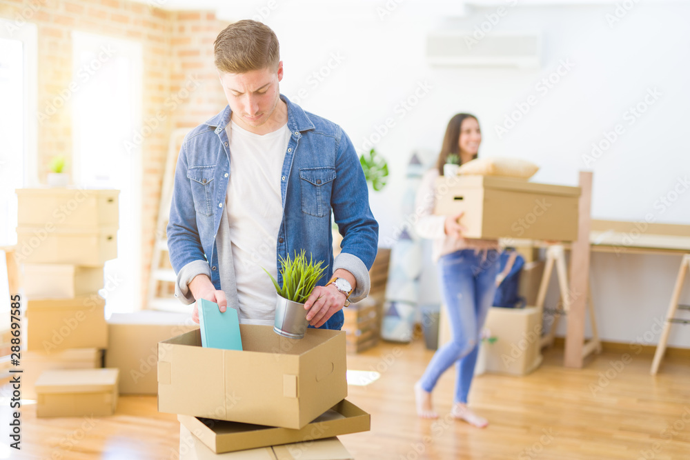 Beautiful young couple smiling in love holding cardboard boxes, happy for moving to a new home