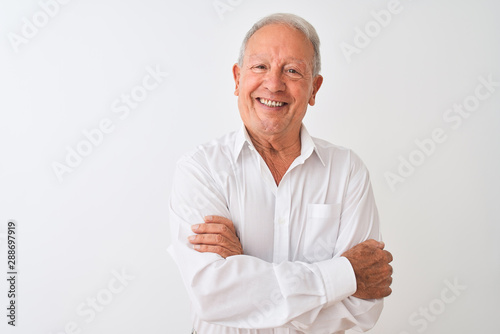 Senior grey-haired man wearing elegant shirt standing over isolated white background happy face smiling with crossed arms looking at the camera. Positive person. © Krakenimages.com