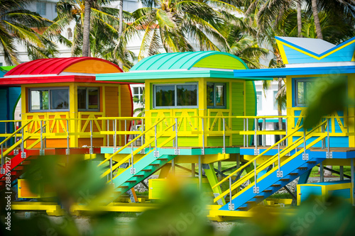Colorful scenic morning view of brightly painted lifeguard towers with coconut palm trees on the South Beach promenade in Miami, Florida, USA