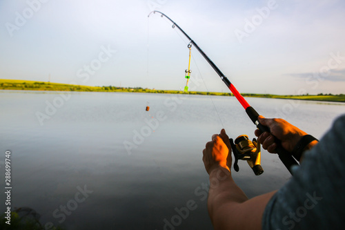 Man is fishing with rods near the lake. Hobby outdoors. Catching fish in the nature with poles.