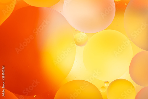 bright oily drops in water with colorful background, close-up 