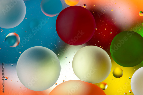 bright oily drops in water with colorful background, close-up 