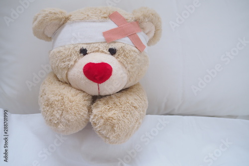 Teddy bear with a wound dress, wound and broken hands. Sleeping in bed. Sickness of children