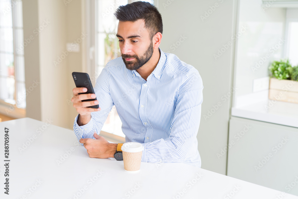 Handsome hispanic business man drinking coffee and using smartphone with a confident expression on smart face thinking serious