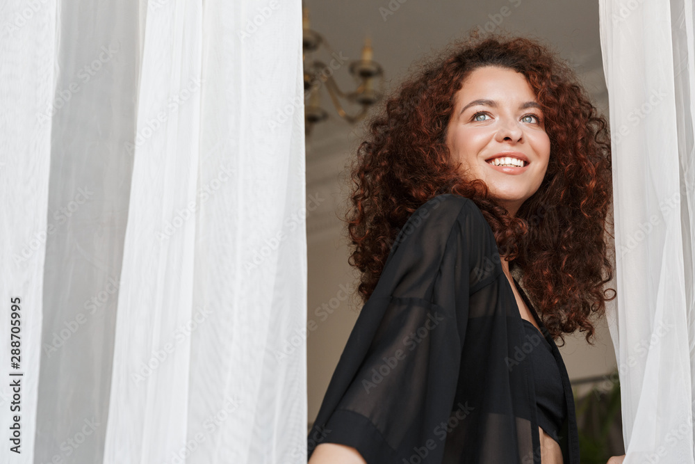 Cheerful woman in lingerie swimwear posing indoors in home hotel near curtain. Cheerful woman in lingerie swimwear posing indoors in home hotel near curtain.