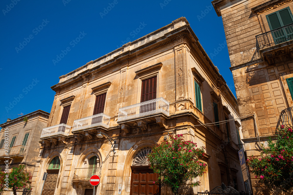 View of old Italian houses with green plants in Ostuni known as the white city, famous tourist destination in Brindisi province, Region Apulia(Puglia), southern Italy. Clear blue sky