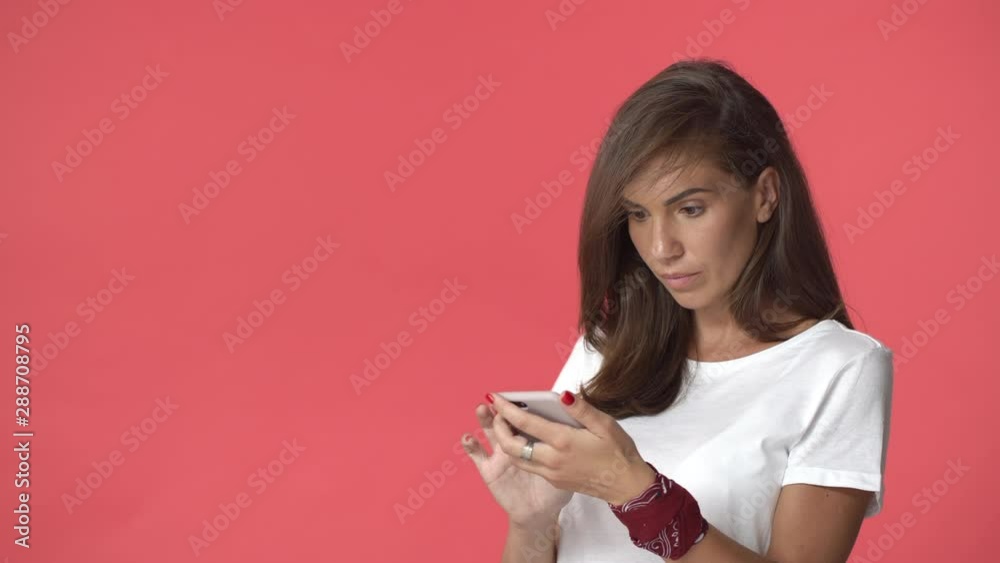 Woman swiping, scrolling through online shop. Attractive adult brunette female in white t-shirt hold smartphone, browsing internet, found something interesting, nod and gesturing in approval Woman swiping, scrolling through online shop. Attractive adult brunette female in white t-shirt hold smartphone, browsing internet, found something interesting, nod and gesturing in approval