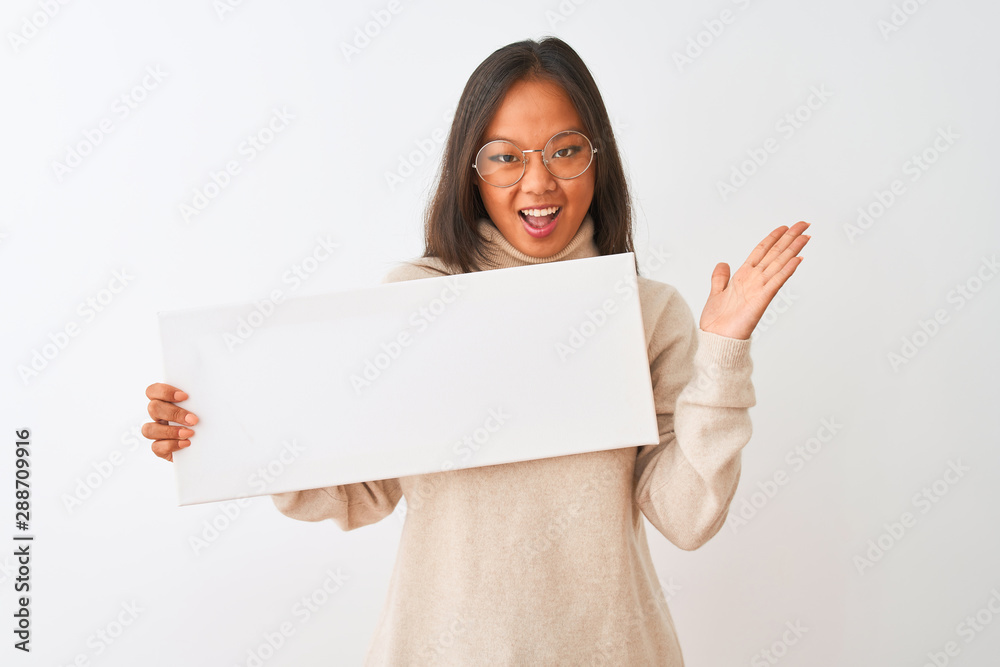 Young beautiful chinese woman wearing glasses holding banner over isolated white background very happy and excited, winner expression celebrating victory screaming with big smile and raised hands Young beautiful chinese woman wearing glasses holding banner over isolated white background very happy and excited, winner expression celebrating victory screaming with big smile and raised hands