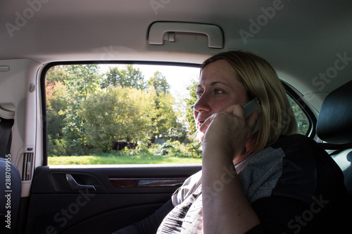 white blonde woman 42 years old in a car with a smartphone in her hands