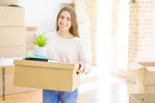Beautiful young woman smiling happy moving to a new home, very excited holding cardboard boxes at new apartment