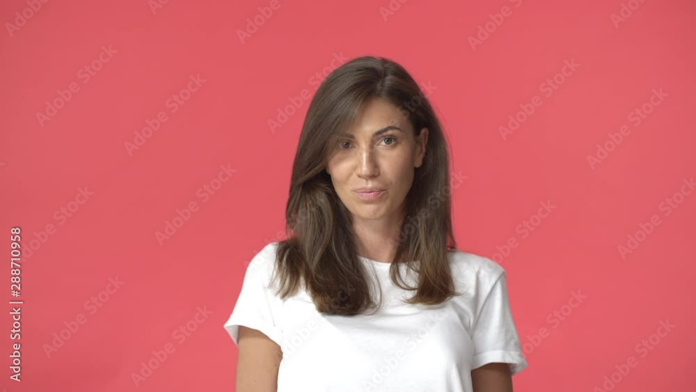 Real people and emotions concept. Adult attractive caucasian brunette woman in yellow t-shirt, standing relaxed with casual expression, red background, slightly smiling camera Real people and emotions concept. Adult attractive caucasian brunette woman in yellow t-shirt, standing relaxed with casual expression, red background, slightly smiling camera