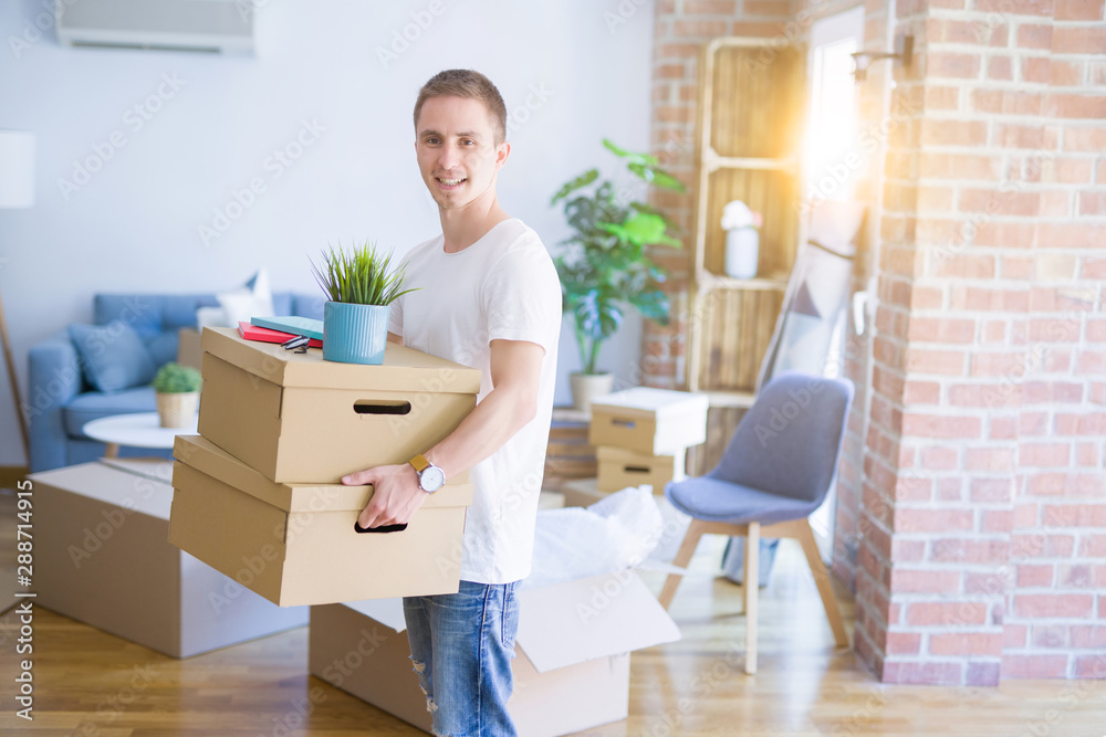 Young handsome man moving cardboard boxes at new home Young handsome man moving cardboard boxes at new home