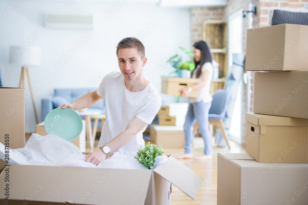 Young beautiful couple open cardboard boxes to order new home Young beautiful couple open cardboard boxes to order new home