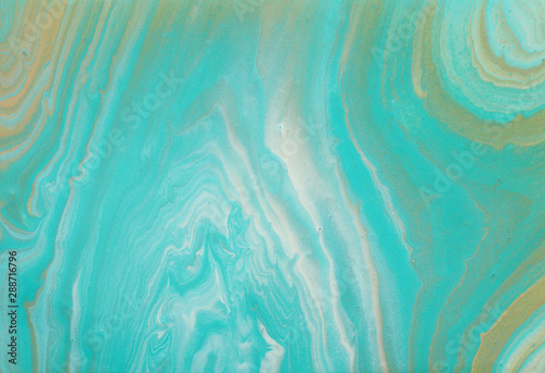 photography of abstract marbleized effect background. turquoise, gold, blue and white creative colors. Beautiful paint.