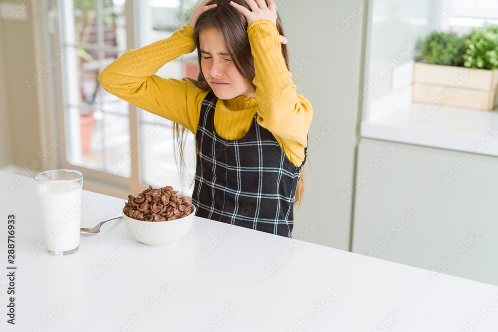 Beautiful young girl kid eating chocolate cereals and glass of milk for