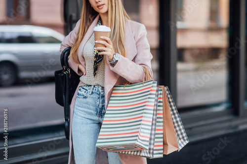 Close up photo. Street look, outfit. Woman with shopping bags. Details. Fashion time near boutique.