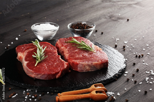 Steak raw. Barbecue Rib Eye Steak or rump steak on dark rustic table photo