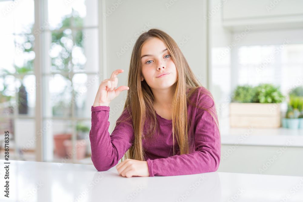 Beautiful young girl kid on white table smiling and confident gesturing with hand doing size sign with fingers while looking and the camera. Measure concept. Beautiful young girl kid on white table smiling and confident gesturing with hand doing size sign with fingers while looking and the camera. Measure concept.